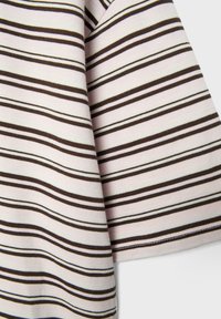 Zbliżenie na beżową tkaninę z równomiernie rozmieszczonymi poziomymi czarnymi i brązowymi paskami, ukazującą teksturę i fałdy.