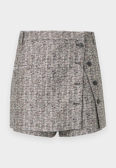 Tweed shorts in a black and white colorway. Features a wrap design with two buttons and a side pocket, textured fabric throughout.