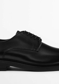Scarpe eleganti in pelle nera con una texture liscia, stringate nella parte anteriore e suola resistente. Presentano un'accurata cucitura lungo i bordi.