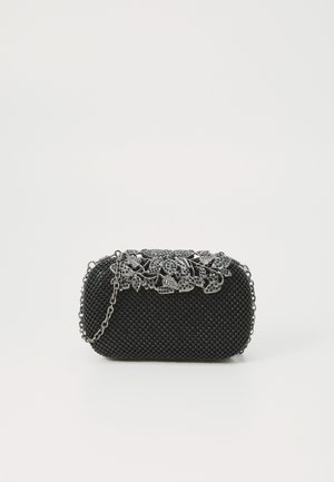 Pochette noire perlée avec fermoir floral argenté et bandoulière chaîne sur fond blanc.