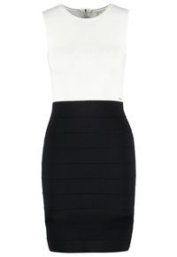 Robe ajustée sans manches avec un haut blanc côtelé et une jupe noire texturée taille haute avec des bandes horizontales.