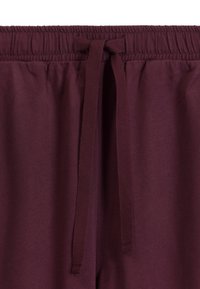 Bordowe spodnie na elastycznej talii mają sznurek do ściągania, miękką teksturę i gładki materiał, idealne do codziennych lub luźnych stylizacji.