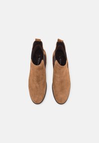 Bottines en daim beige avec dessus lisse, panneaux latéraux élastiques et languette pour tirer, dotées d'une semelle en caoutchouc marron. Taille 37 visible à l'intérieur.