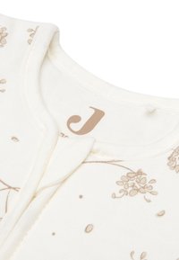 Lichte crèmekleurige katoenen cardigan met een bloemenpatroon in zacht beige. Heeft een ronde halslijn en een drukknoopsluiting aan de voorkant.