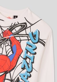 Biała bawełniana koszulka z grafiką Spider-Mana w czerwono-niebieskich kolorach, otoczona czarnymi wzorami pajęczyn oraz niebieskim tekstem. Krótkie rękawy.