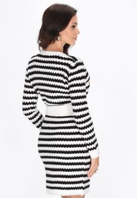 Rochie tricotată cu dungi în alb și negru, textură ștanțată, design ajustat, mâneci lungi, cu decolteu rotund și o siluetă scurtă.