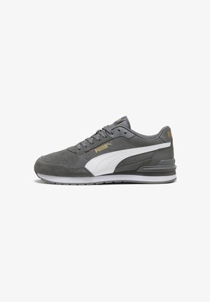Sneaker Puma grigio con striscia bianca laterale, logo Puma dorato, design con lacci e suola imbottita, mostrato in profilo su uno sfondo bianco.