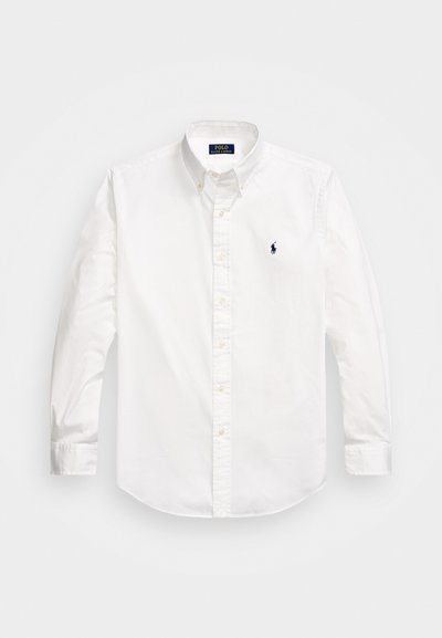 Λευκό πουκάμισο μακρυμάνικο από βαμβάκι, με κολάρο που κουμπώνει, μπροστινή πλαϊνή σειρά κουμπιών και μικρό ναυτικό λογότυπο στο αριστερό στήθος.
