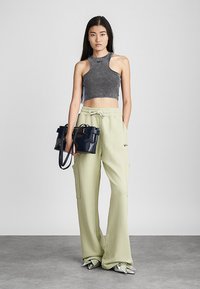 Grå cropped top, lysegrøn cargo-bukser med lommer og sort håndtaske, afsluttet med sølvfarvede flade sko, præsenteret mod en neutral baggrund.