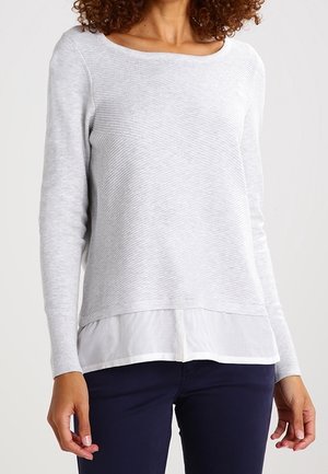Hellgrauer Pullover mit gerippter Textur, rundem Ausschnitt und geschichtetem weißen Saum. Lange Ärmel und eine lockere Passform.