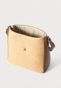 Geflochtene Strohtasche mit einem Basis und Riemen aus hellbraunem Leder. Offenes Oberdesign mit beigem Stofffutter und goldenen Hardware-Akzenten.