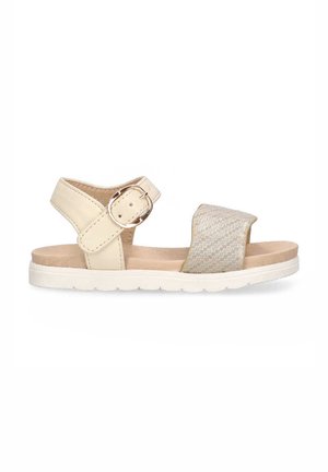 Sandalia beige con un acento plateado texturizado. Presenta una correa ajustable en el tobillo con una hebilla redonda y una suela de goma blanca.