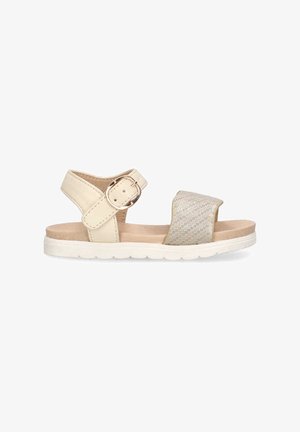 Sandalia beige con un acento plateado texturizado. Presenta una correa ajustable en el tobillo con una hebilla redonda y una suela de goma blanca.