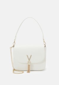 Bílá taška z umělé kůže s klopou, zlatým kováním a řetízkovým popruhem. Vyznačuje se detailem ve tvaru "V" a dekorativní třásní.