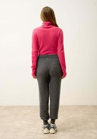 Rosa poloccktröja i ullblandning; grå sweatpants i mjukt tyg; sportskor med mörkgrå och beige detaljer.