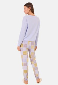Lichtblauw long-sleeve shirt in combinatie met een gestreepte pyjamabroek met vierkanten in lavendel, geel en wit. Comfortabele stof, ontspannen pasvorm.