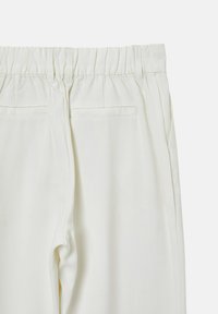Pantalons blancs, légers, avec une taille élastique, présentant deux poches arrière et une texture lisse. Design simple et taillé.
