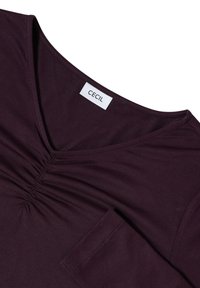 V-neck purple top with gathered center detail and a chest pocket. Made from soft, smooth fabric. Brand label reads "CECIL."