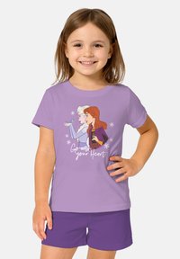 T-shirt viola con personaggi animati e la scritta "Segui il tuo cuore", con maniche corte e scollatura tonda. Abbinato a pantaloni corti viola.