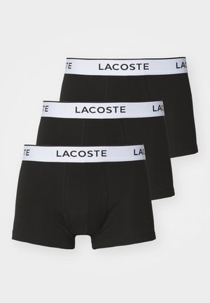 Črne bokserice v paketu treh, z belim elastičnim pasom, na katerem je v črni barvi napisan "LACOSTE". Mehko, elastično bombažno blago.