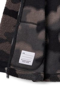 Giacca in pile con zip in grigio e nero con motivo camouflage. Presenta un'etichetta con la scritta "Giocando all'aperto dal 1938." Tessuto morbido e texturizzato.