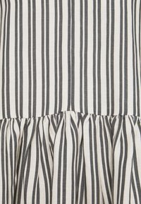 Gestreifter Stoff in Creme und Dunkelgrau, mit vertikalen Linien und einem gerafften Saum. Das Material wirkt texturiert und gewebt.