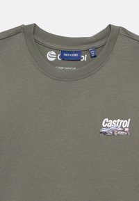 Πράσινο ελαιούχου χρώματος T-shirt από βαμβάκι, με στρογγυλή λαιμόκοψη και μικρό εκτυπωμένο γραφικό με αυτοκίνητο και το λογότυπο "Castrol" στο μπροστινό μέρος.