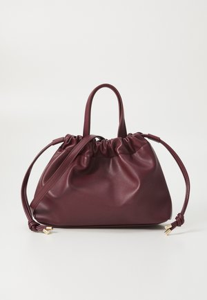 Sac à main en cuir bordeaux doux avec côtés à cordon, deux petites poignées supérieures et une bandoulière réglable avec embouts en métal doré.