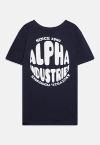 Tamsiai mėlynas medvilninis marškinėliai trumpomis rankovėmis su dideliu baltu tekstu: "ALPHA INDUSTRIES" ir "SINCE 1959" kreiviame dizaino stiliuje.