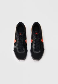 Melnas sporta kurpes ar sietiņa un sintētiskajiem materiāliem, kas piedāvā oranžu Nike zīmolu. Profilēta gumijas zole, sasaistāma dizaina un mīkstināts zolītes iekšpuse.