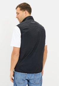 Czarna bezrękawnik wykonana z lekkiego materiału, z wysokim kołnierzem, bezszwowym ramionami i detalem logo na plecach.