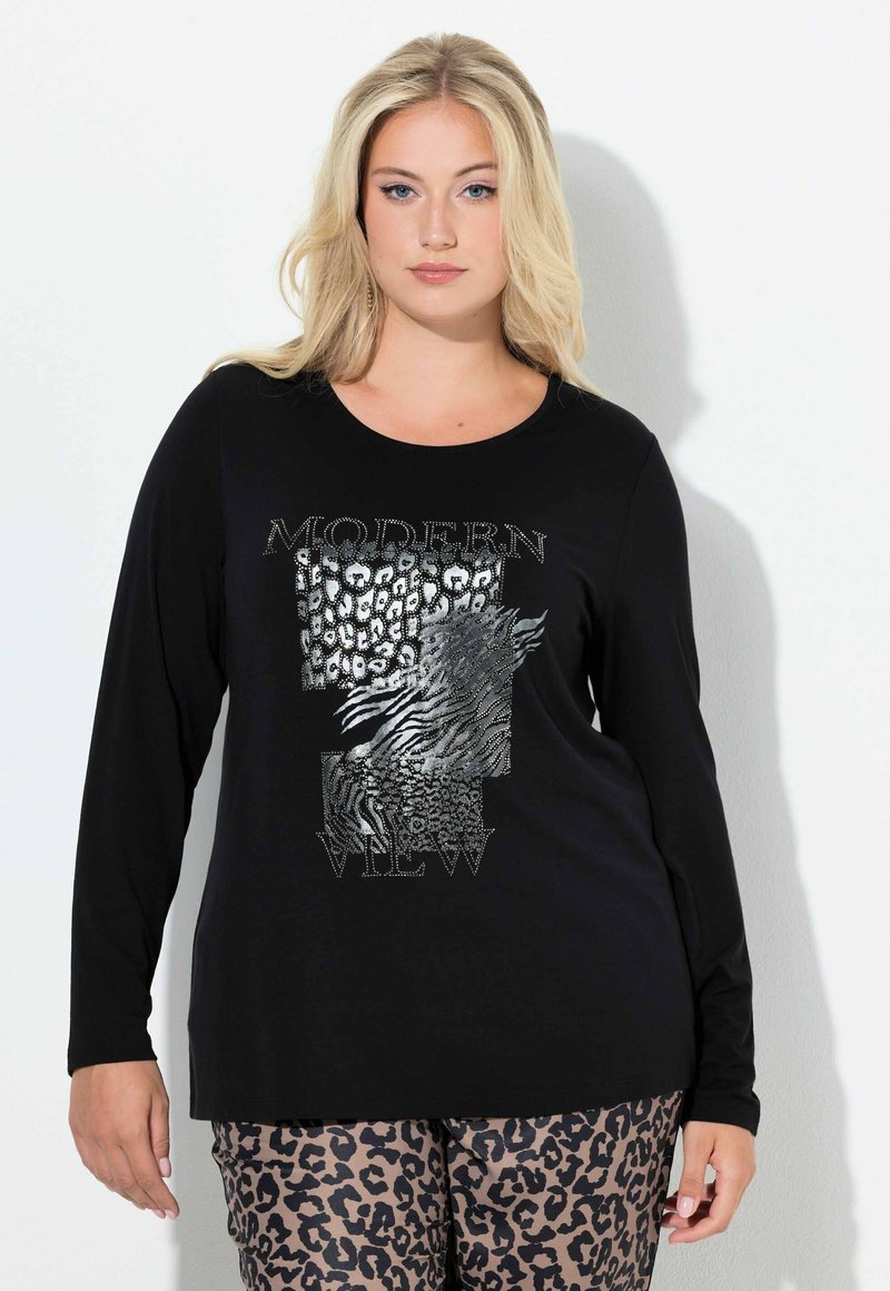 Czarna koszulka z długim rękawem z grafiką z srebrnymi akcentami i teksturowanym wzorem zwierzęcym, w połączeniu z spodniami w panterkę.
