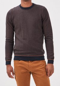 Suéter azul marino con un patrón de diamantes texturizado, que cuenta con un cuello redondo y puños acanalados, complementados con detalles de costuras contrastantes en color naranja.