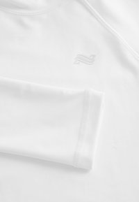 Vit långärmad skjorta i glatt material. Har en diskret logga i ljusgrått och platta sömmar för en ren finish.