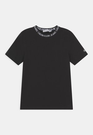 Sort T-shirt med korte ærmer og rund halsudskæring med gentagende hvid "Calvin Klein Jeans" tekst og lille CK-logo på venstre ærme.