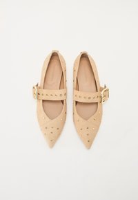 Pantofi bej din suede, cu vârfuri ascuțite și curea la gleznă. Prezintă accente cu cui aurii și sistem de închidere cu cataramă. Fodera interioară este netedă.