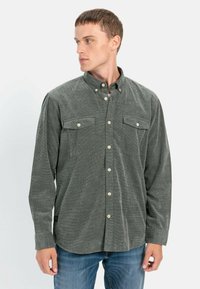 Langärmliges Button-Down-Hemd aus dunkelgrünem Stoff mit strukturierter Oberfläche, ausgestattet mit zwei Brusttaschen und klassischem Kragen.
