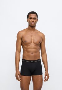 Zwarte boxershorts gemaakt van zachte stof, met een elastische tailleband bedrukt met een logo. De pasvorm is nauwsluitend, waardoor ze een krappe vorm bieden.