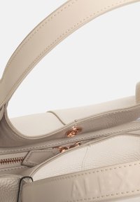 Borsa in pelle beige con finitura testurizzata, dotata di zipper e accessori in oro rosa. Include una tracolla larga e piatta e una chiusura liscia.