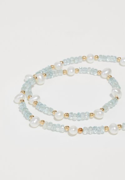 Κολιέ με χάντρες που διαθέτει ανοιχτό μπλε πέτρες, στρογγυλές λευκές πέρλες και χρυσές λεπτομέρειες, τοποθετημένες σε στρωματοποιημένο σχέδιο με ποικιλία σχημάτων και μεγεθών.