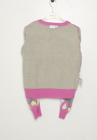 Rückansicht eines gestrickten beigen Sakkos mit pinkem Kragen und Saum, floral gemusterten Ärmeln in Pink, Gelb, Grün und Weiß, auf einem klaren Kleiderbügel.