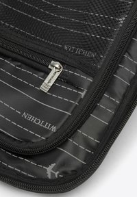Schwarze Reisetasche mit diagonaler Streifenmuster, strukturiertem Oberflächen, Reißverschlussverschluss und Logodetail. Weiches Material mit einem Mesh-Overlay.