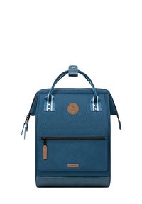 Blue backpack with textured fabric, a front zipper pocket, leather accents, and a braided top handle. Features striped straps on the sides.