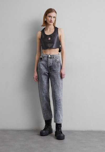 Black cropped top with a square neckline and chains on straps, paired with high-waisted gray denim jeans and chunky black platform boots.