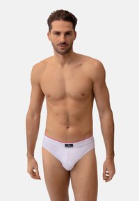 Weiße Slips mit einem roten Bund, versehen mit einem schwarzen Logopatch. Hergestellt aus dehnbarem Stoff, der für einen enganliegenden Sitz um die Taille konzipiert ist.