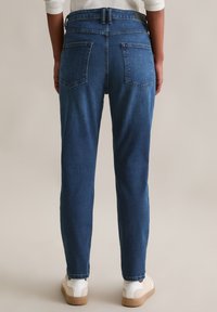 Blauwe denimbroeken met een recht model, vijf zakken en een iets taps toelopende enkel. Afgewerkt met een standaard tailleband en riemlussen.