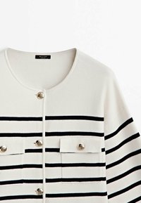 Vit randig cardigan med marinblå horisontella ränder, två framfickor med metallknappar och rund halsringning. Mjuk textur.