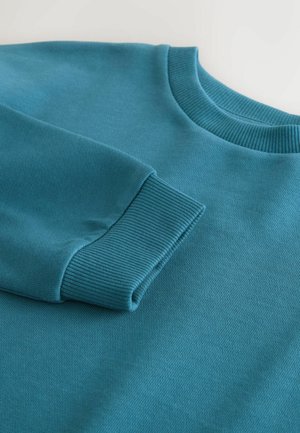 Pulover teal cu guler și manșete cu textură canelată. Textură netedă, având o croială relaxată, fără modele vizibile sau detalii de hardware.