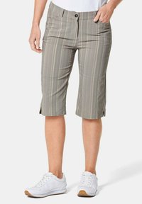 Grijze geruite bermuda shorts met een platte voorkant, twee zakken en zijsplits aan de zoom. Gepaard met witte sportschoenen.