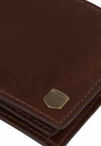 Portefeuille en cuir marron avec un plaquette logo en métal texturé, des détails cousus et un design mince avec plusieurs emplacements pour cartes.